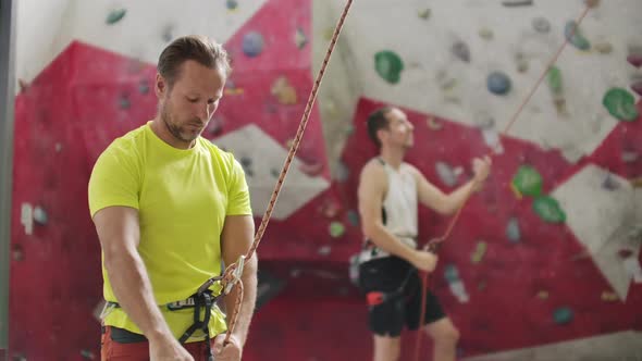 Man Belaying Another Climber on an Indoor Climbing Wall