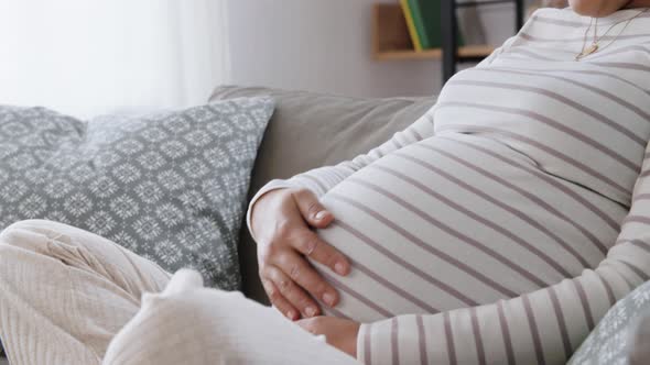 Happy Pregnant Asian Woman Sitting on Sofa at Home