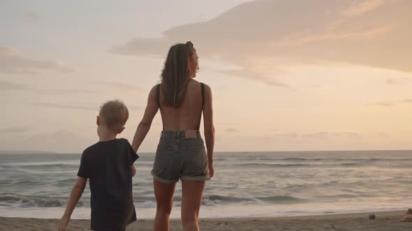 Mother and Son Walking Along Beach at Sunset