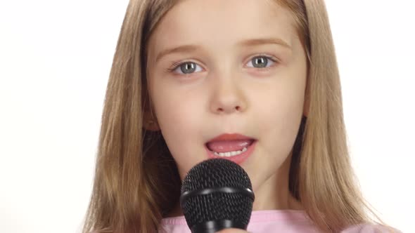 Child Girl Sings the Song Into the Microphone. White Background. Close Up