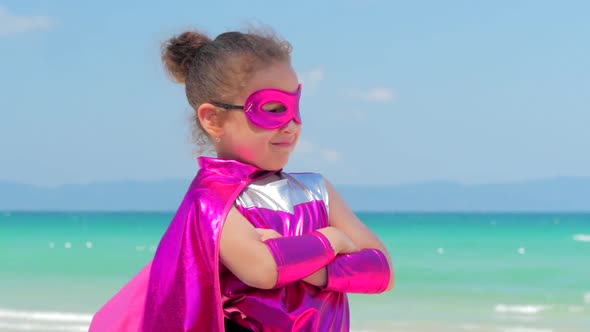 Beautiful Little Girl in the Superhero Costume, Dressed in a Red Cloak and the Mask of the Hero