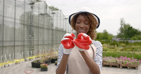 Young Female Florist Put on Gardening Gloves