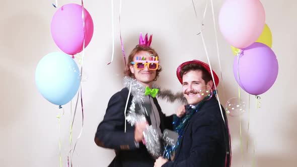 Friends having fun dancing with boards in love in photo booth