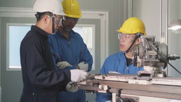 Asian mechanical technicians workers working on milling machine and operating the machine in factory