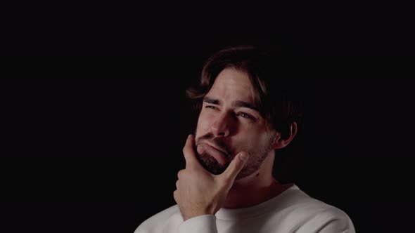 Trendy Young Man rubbing chin and thinking, close, black background