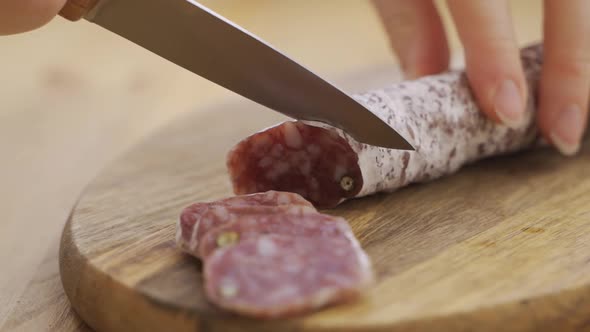 Slicing Spanish Traditional Homemade Chorizo Sausages Into Pieces on a Wooden Cutting Board in the