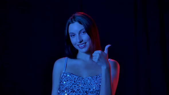 Portrait of Charming Young Woman Is Looking at Camera Smiling Shows Ok and Thumbs Up Gesture. Close