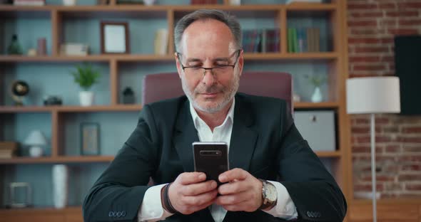 Businessman Typing Texting Message on Phone During His Work in Modern Office