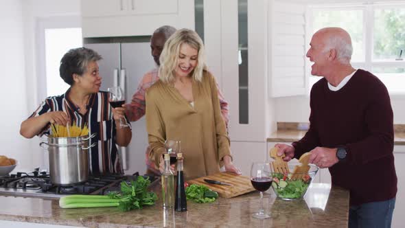 Diverse senior couples preparing vegetable salad in a kitchen