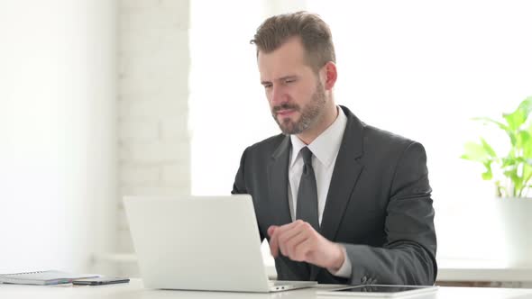 Young Businessman Having Wrist Pain While Using Laptop in Office