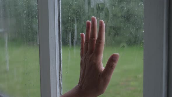 Hand Touches Window Glass And Slides Down Side Behind Which It Is Raining