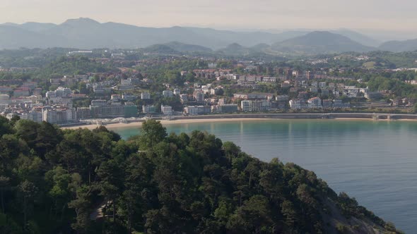 Cityscape of San Sebastian surrounded by hilly landscape, aerial cinematic view