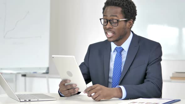 African Businessman Talking on Online Video Chat Via Tablet