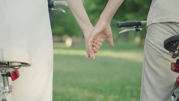 Unrecognizable Mid-adult Couple Holding Hands in Summer Park