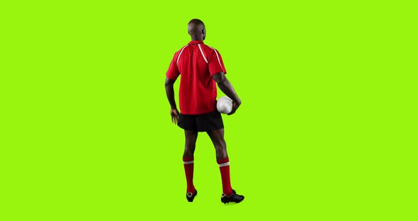 Professional Rugby Player Standing and Holding a Ball on Green Background