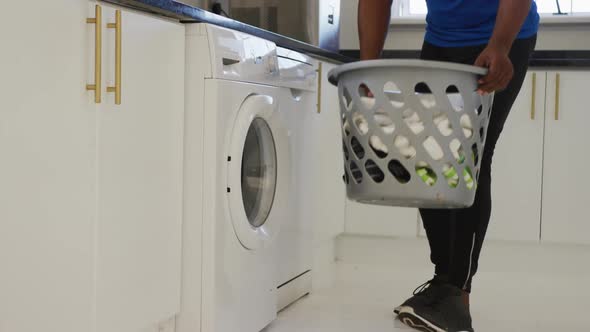 African american senior man putting dirty laundry into washing machine at home