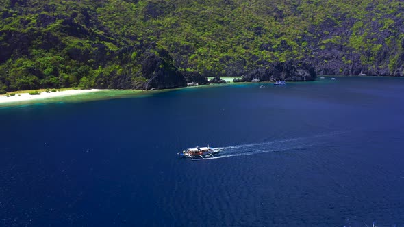 Aerial Drone View of White Traditional Filipino Boat Floating on Top of Clear Blue Water Surface