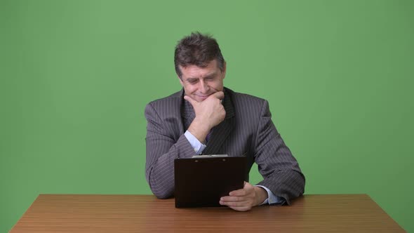 Mature Handsome Businessman Against Green Background