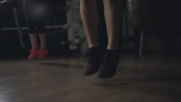 Close-up of Male Caucasian Feet Jumping Rope in Dark Gym. Unrecognizable Young Woman Exercising at