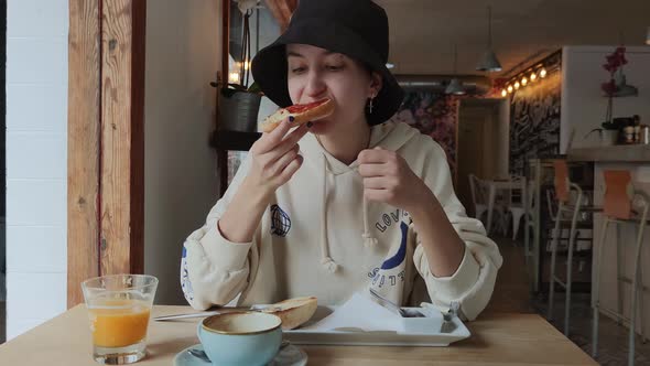 a Girl Has Breakfast in a Cafe