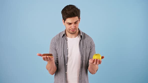 Male Taking Out Apple and Donut From Behind His Back Thinking What Should He Eat