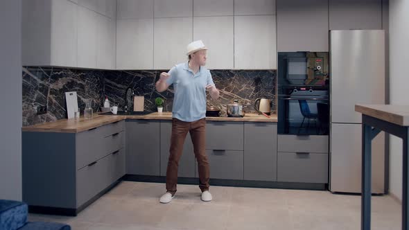 Crazy Dance of a Man in a Hat Dancing in the Background of the Kitchen