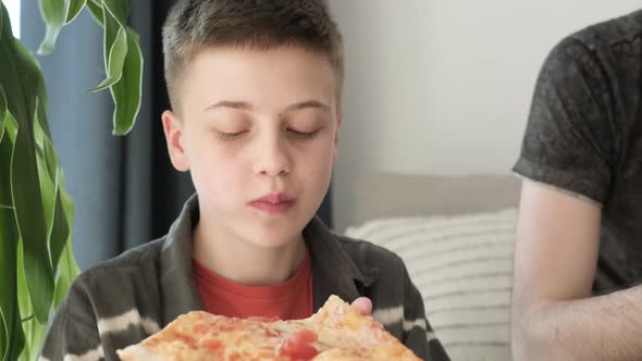 Family Eating Pizza Sitting on Sofa at Home