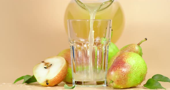 Pear Juice Is Poured From a Jug Into a Glass. 