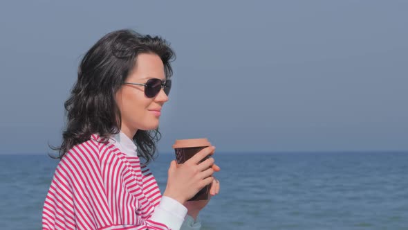 Young Woman with Cup of Hot Beverage on Beach