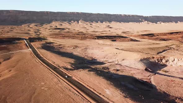 Stunning Aerial Cinematic Shot of Cars Driving Along a Desert Road