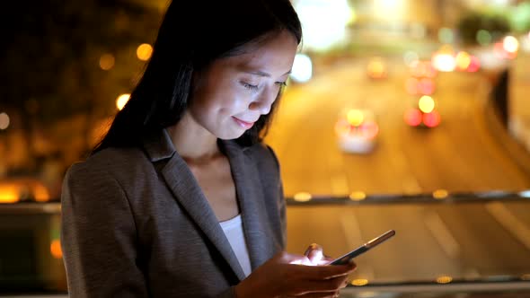 Business woman using smart phone in city at night 