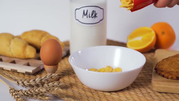 Sprinkling Cornflakes in a White Ceramic Bowl