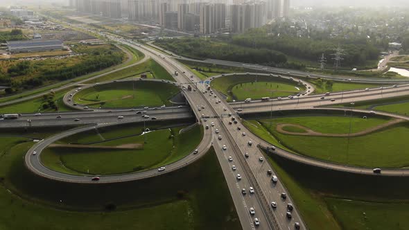 Aerial View of a Large Roundabout with Moving Cars on the Background of the City