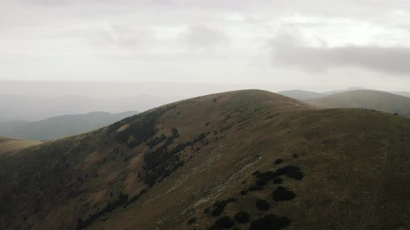 Flying over dry peak covered with little greenery, Wide aerial shot, Slovakia