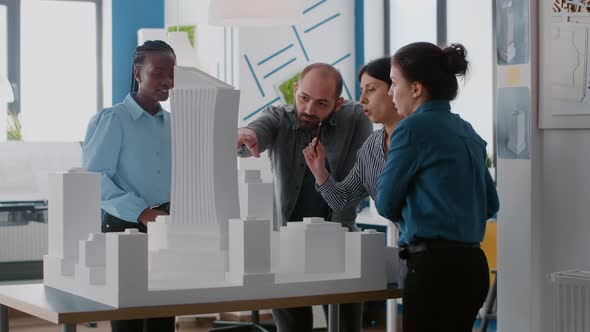 Group of Diverse Colleagues Pointing at Building Model to Work on Architectural Urban Project