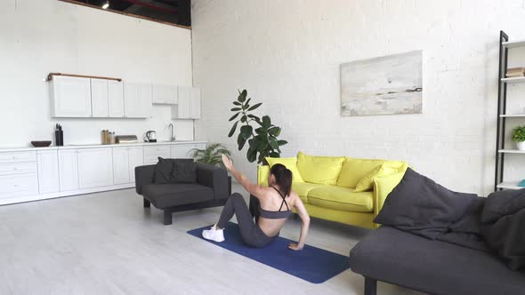 Beautiful Young Woman Doing Exercises on the Floor at Home