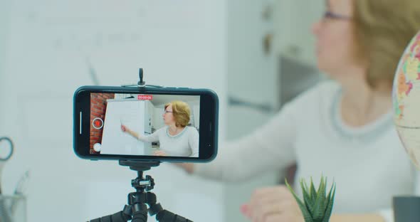 Adult Woman Sitting at the Table and Records a Video Lesson on the Phone