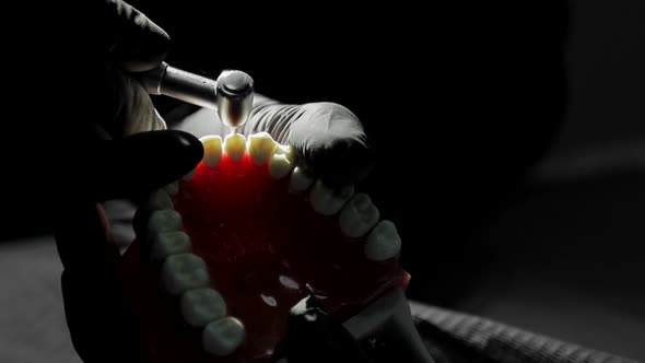 Close-up of a Dentist Practicing on a Mock-up of a Skeleton of Teeth Using a Drill Machine. the