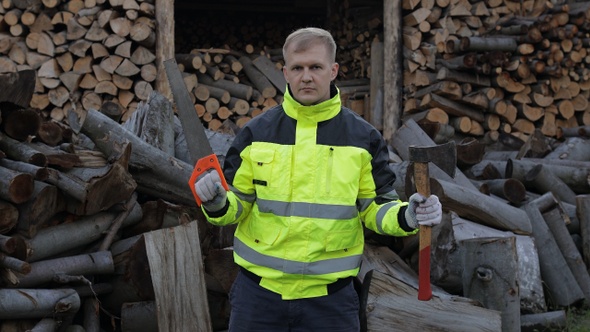 Lumberjack in Reflective Jacket. Man Woodcutter Holds Small Axe and Saw on His Hands. Firewood