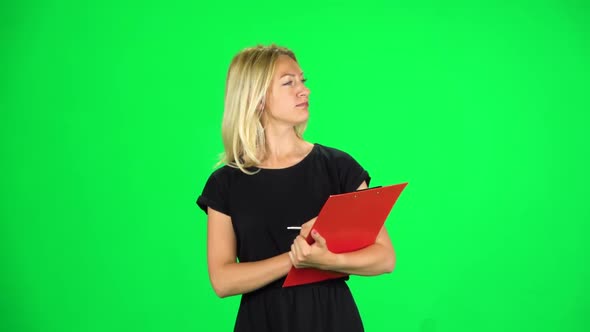 Woman with a Red Folder Goes Carefully Looking Around and Taking Notes, Chroma Key. Slow Motion