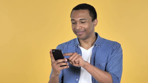 Young African Man Browsing Smartphone Yellow Background