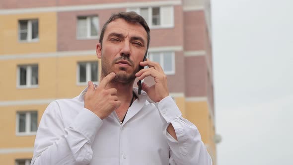 Focused Businessman in a White Shirt Speaks on the Phone