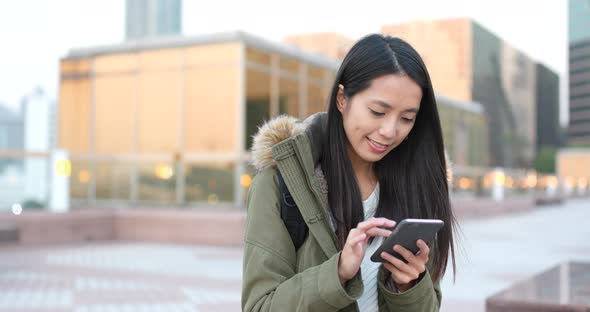 Woman use of mobile phone in the city at winter time