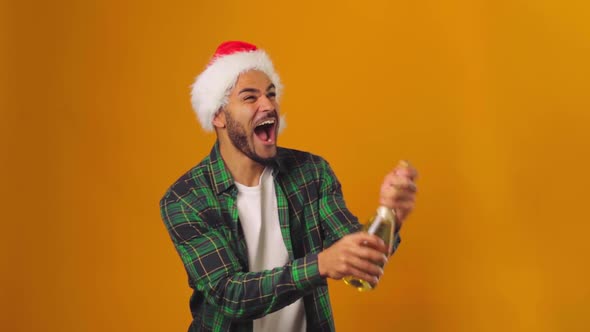 African American Man in Santa Hat Opening Champagne Bottle with Explosion Against Yellow Background