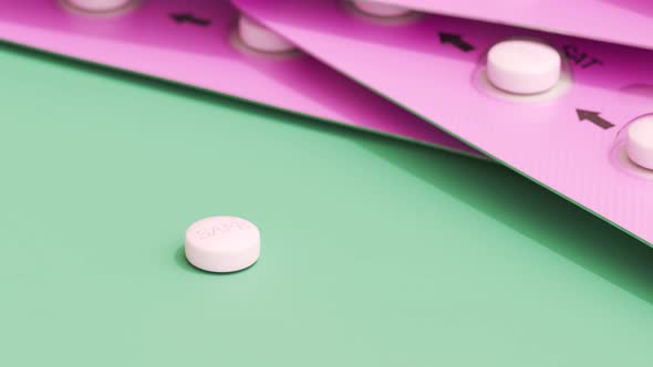 Pink birth control pill on a green table. Pills in a feminine  blister. 4KHD