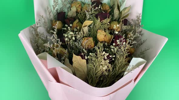 Romantic composition of dried flowers. Dried roses in slow motion on a green background.