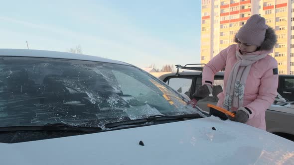 Woman Removing Ice From Car Window with Ice Scrap