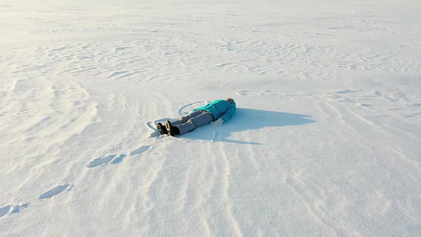 A Girl Makes a Figure of a Snow Angel in a Clearing in the Forest