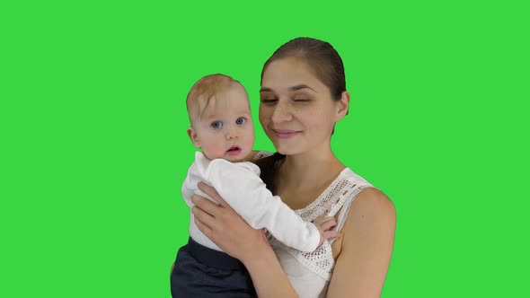 Mother Holding Her Child and Looking in To Camera Smiling on a Green Screen, Chroma Key