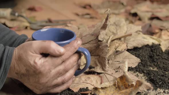 Dirty pair of cold hands warming on a hot drink